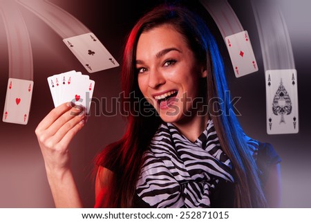 Beautiful brunette lady showing poker of aces and gesturing winning in casino