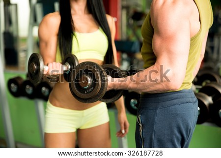 Fitness couple working out in gym with dumbbells