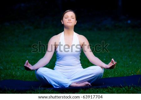 Meditation in nature - Cute young girl meditates outdoor on a green grass field