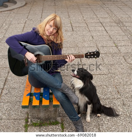 Young female guitar performer posing with her instrument and her dog
