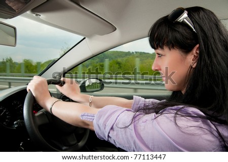 Beautiful young woman drives a car on a highway