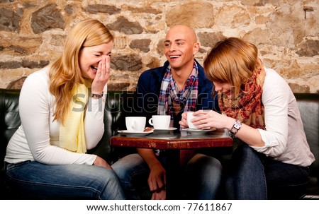 Three friends in cafe discussing and having fun