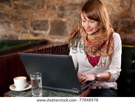 Morning coffee in internet cafe - Beautiful young girl checking news on web and drinking coffee