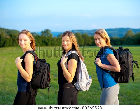 Three cute girls on a hike in nature - three women with backpacks on a trip