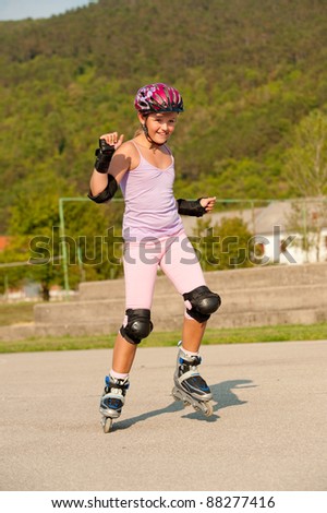 Cute young girl rollerskates on a playground