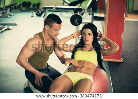 Personal fitness coach trains beautiful woman in gym