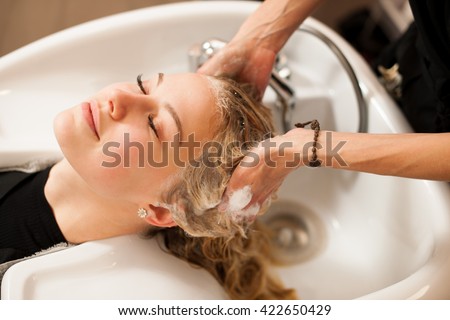 Hair stylist at work - hairdresser washing hair to the customer before doing hairstyle