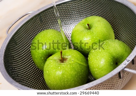 the colander with apples under tap water