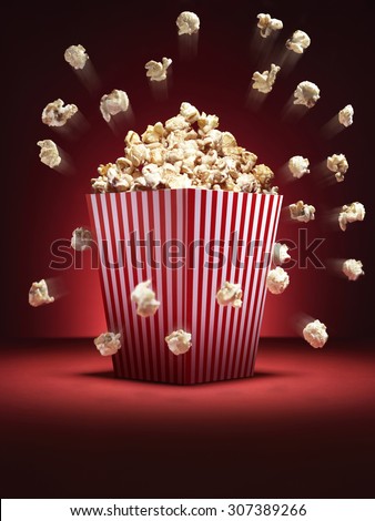 Cinema style popcorn in a traditional box with pieces flying out it a comedy fashion. Vignette effect is naturally created with lighting. There is copy space for the designer at the bottom.