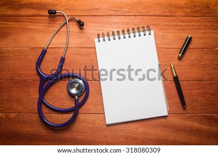 blank white paper of note book with black ink pen and stethoscope on wooden table