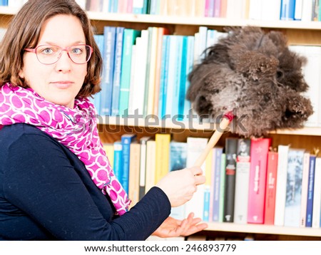 Woman cleans bookshelf with duster of peacock feathers
