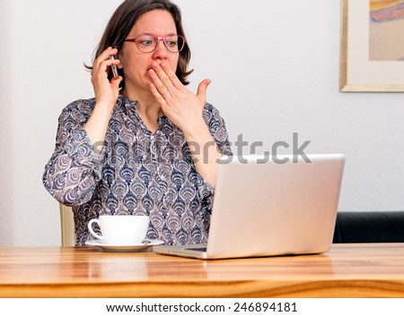 Woman in front of laptop is shocked by email