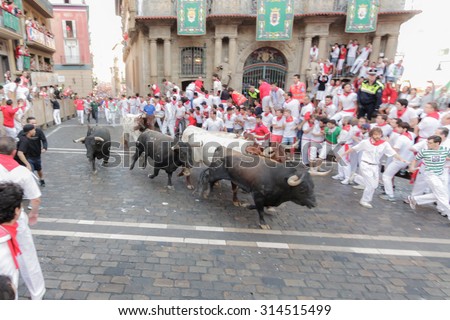 PAMPLONA, SPAIN - JULY 12: People run from bulls on street during San Fermin festival in Pamplona, Spain on July 12, 2015