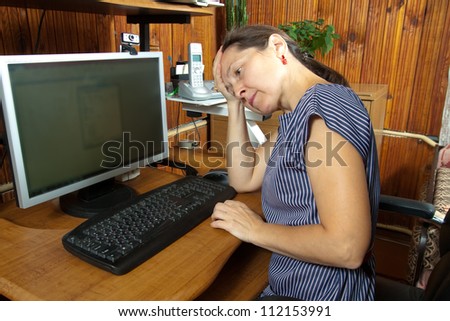 Middle-aged woman tired at computer at home
