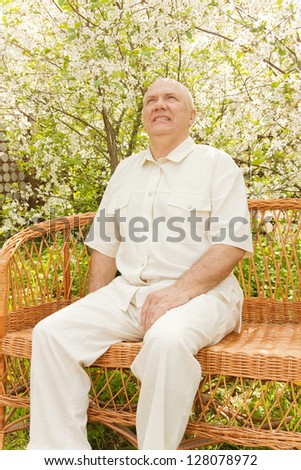 man sitting on   wicker sofa  in   garden