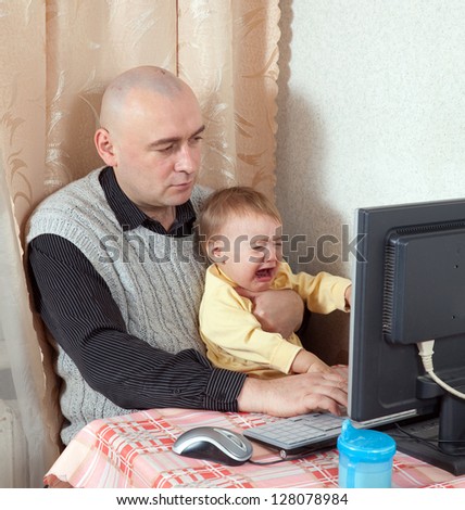 man with crying baby working with computer at home