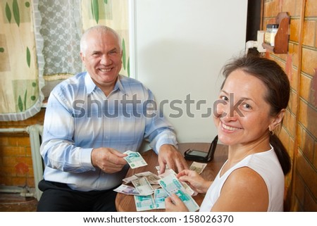Elderly woman and man counting money at the table