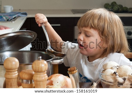 Three years-old child cooking in kitchen