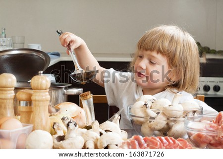 Three years-old child cooking in kitchen