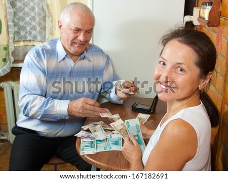 Elderly woman and man counting money at the table