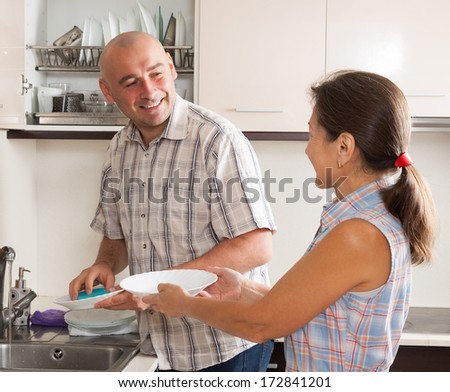 Family washing plates with sponge in domestic kitchen
