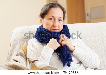 unwell woman in scarf sitting at home