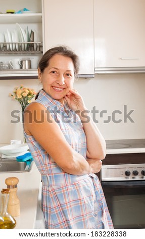 Mature woman smiling at her big kitchen