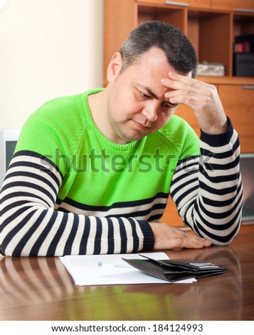 serious man counting his money at  table at home