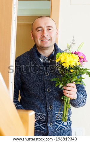 smiling man with  bouquet of flowers near  door