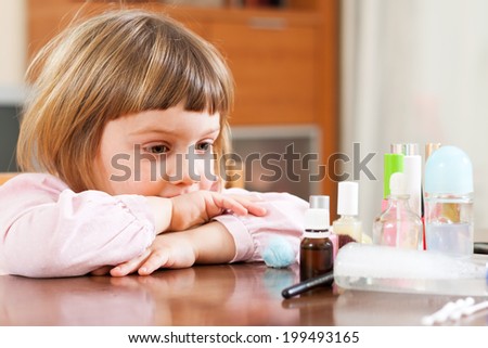 little girl at  table with cosmetic products