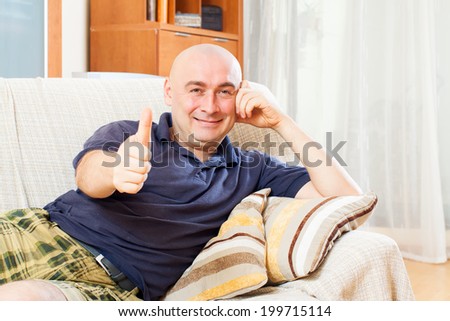 Relaxed man sitting on couch with thumbs up