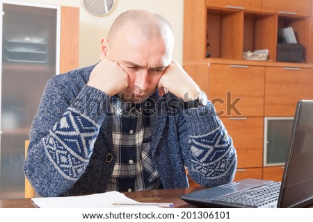 Sad man  sitting at  computer in  home interior.