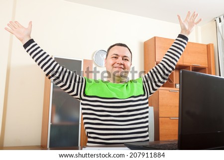 Happy man  sitting at  computer in  home interior.
