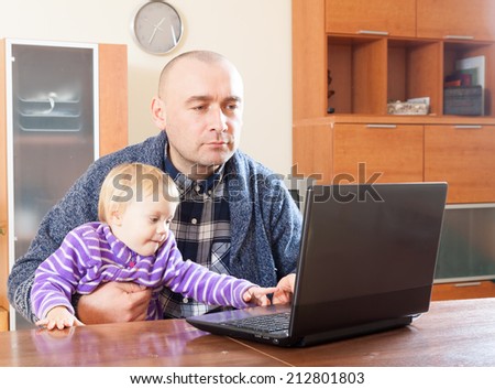 dad  at  laptop with  young daughter on his lap