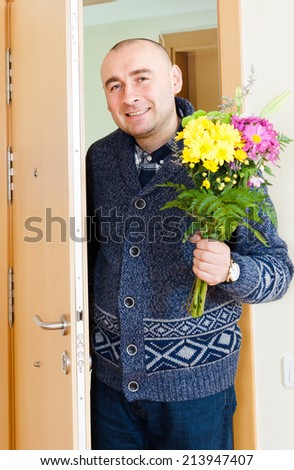 Joyful man with  beautiful bouquet near  front door