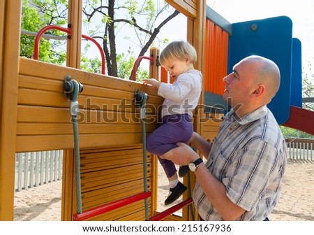 Dad helping his  daughter to climb  ladder on  playground.