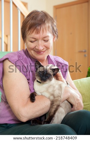 older woman with  Siamese cat in  arms.
