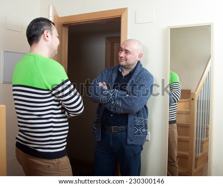 Adult man meeting another man at  door