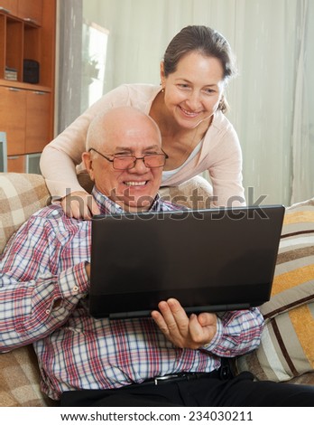 middle-aged man and woman sitting on  couch with  laptop