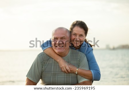 Senior couple on  beach in  sunset rays of  sun.