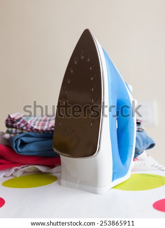 Iron on ironing board with different clothes