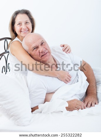 Mature man and woman on bed in bedroom.