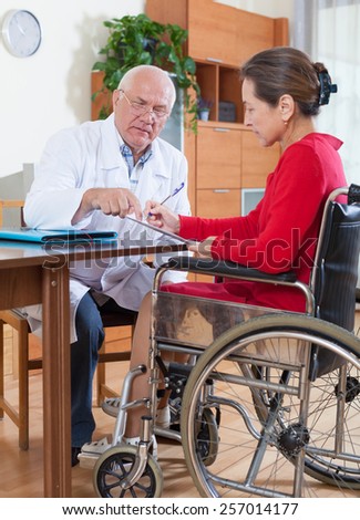 doctor discussing documents with disabled women.