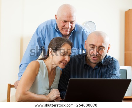 Three smiling people sitting at work on  laptop