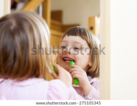 three year old child  painted cosmetics front of  mirror
