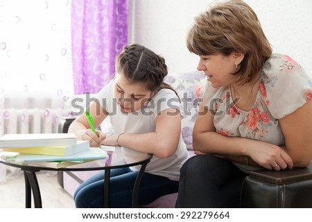 Mature mother helping her child with homework at home.