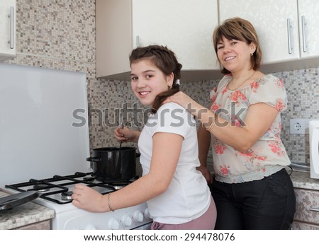 Mom and daughter in   kitchen preparing soup