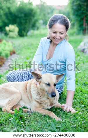 Beautiful woman in   age with   dog on   lawn.
