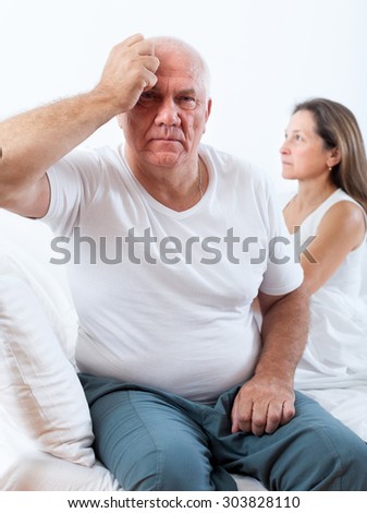offended  man sitting on   bed next to   frustrated woman.
