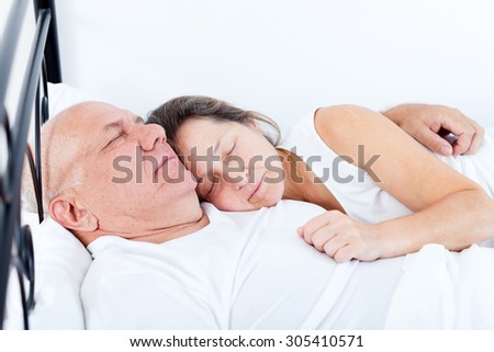 Senior  man and   woman sleeping on   bed in   embrace.